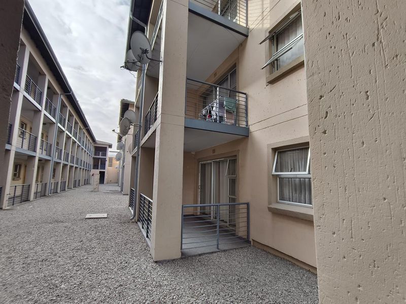 Exterior view of an apartment complex featuring private balconies with metal railings, sliding glass doors, and top-hung windows.