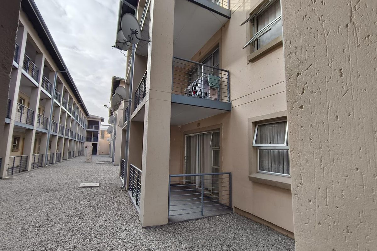 Exterior view of an apartment complex featuring private balconies with metal railings, sliding glass doors, and top-hung windows.