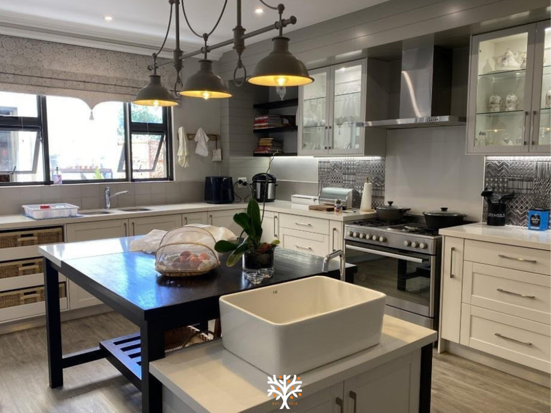 Modern kitchen featuring a large central island, farmhouse sink, gas stove with extractor, and high-quality cabinetry with stone countertops.