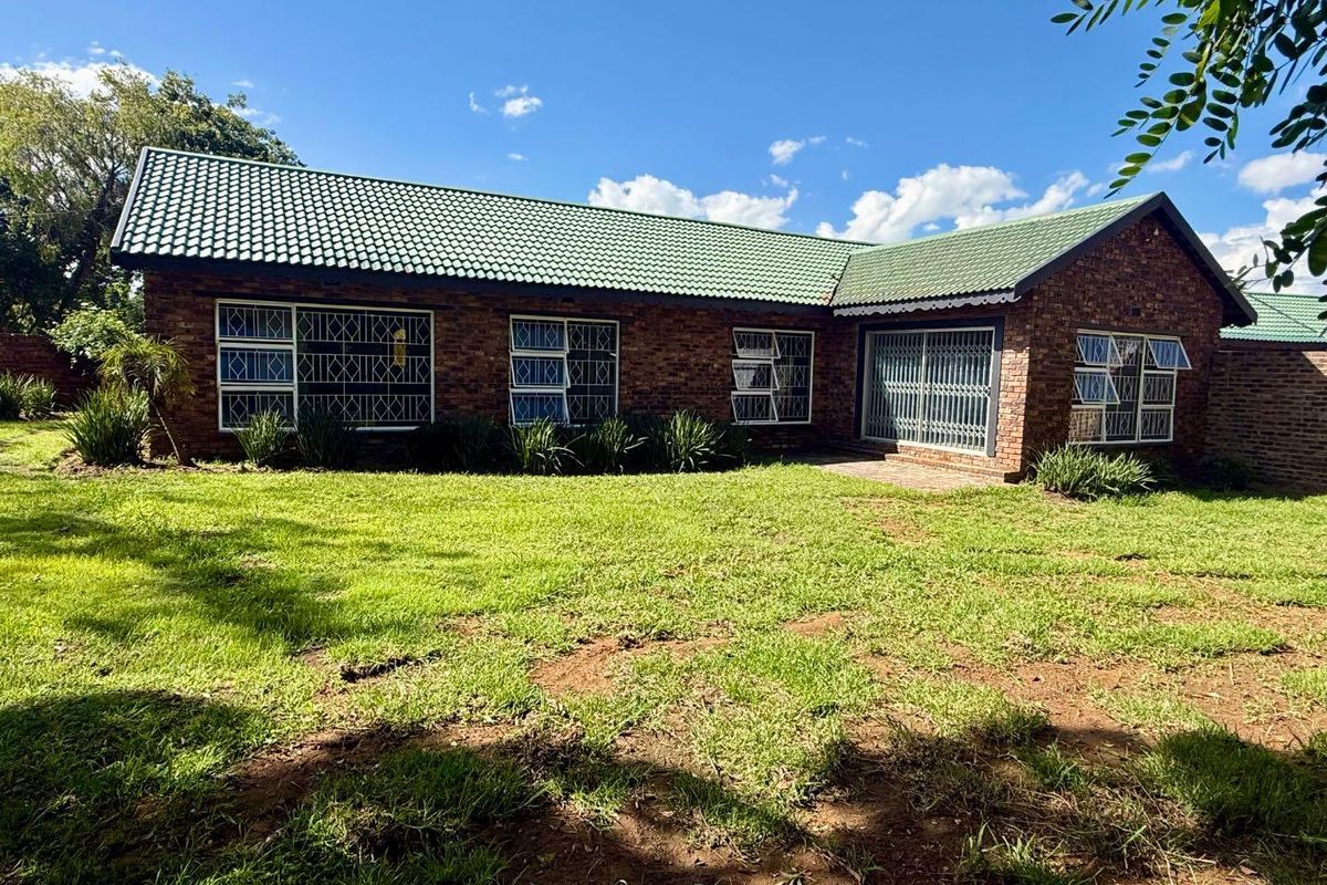 Rear view of a face brick house featuring a pitched tiled roof, security bars on windows, and a sliding door leading to the garden.