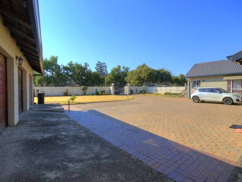 Spacious paved driveway leading to a garage, featuring a perimeter wall and well-maintained exterior grounds.