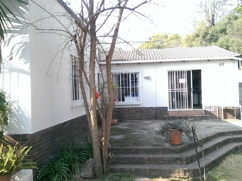 Rear exterior view of the office building featuring a concrete patio, brick steps, and security bars on the windows.