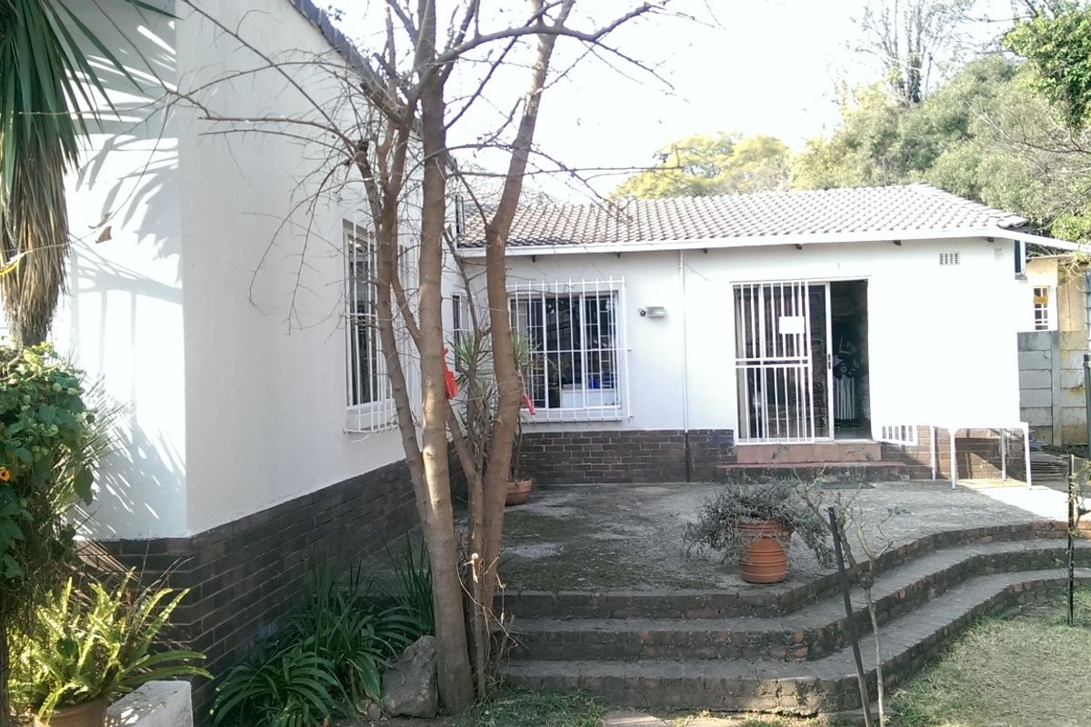 Rear exterior view of the office building featuring a concrete patio, brick steps, and security bars on the windows.