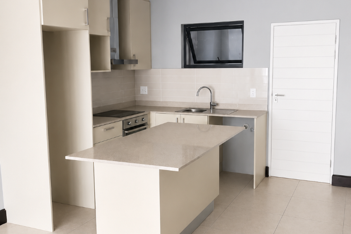 Modern, clean-lined kitchen featuring neutral cabinetry, stone countertops, a functional island, and integrated appliances, presented in a bright, vacant space.