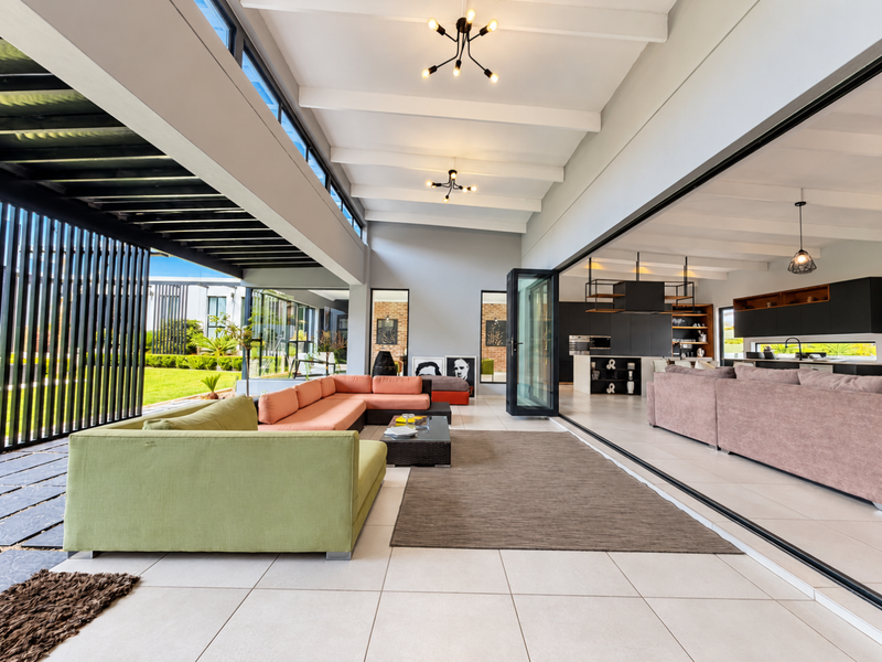 Spacious open-plan living area featuring high exposed beam ceilings, large format tiling, and seamless indoor-outdoor flow through expansive stacking glass doors.
