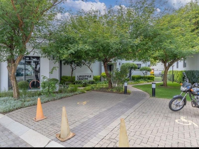 Exterior view of the apartment complex lifestyle centre featuring a paved entrance, landscaped trees, and clear signage.