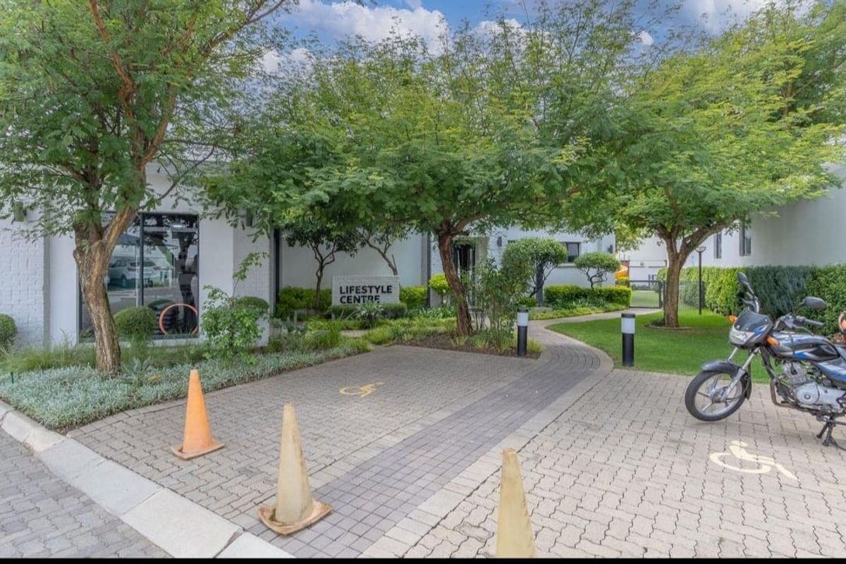 Exterior view of the apartment complex lifestyle centre featuring a paved entrance, landscaped trees, and clear signage.