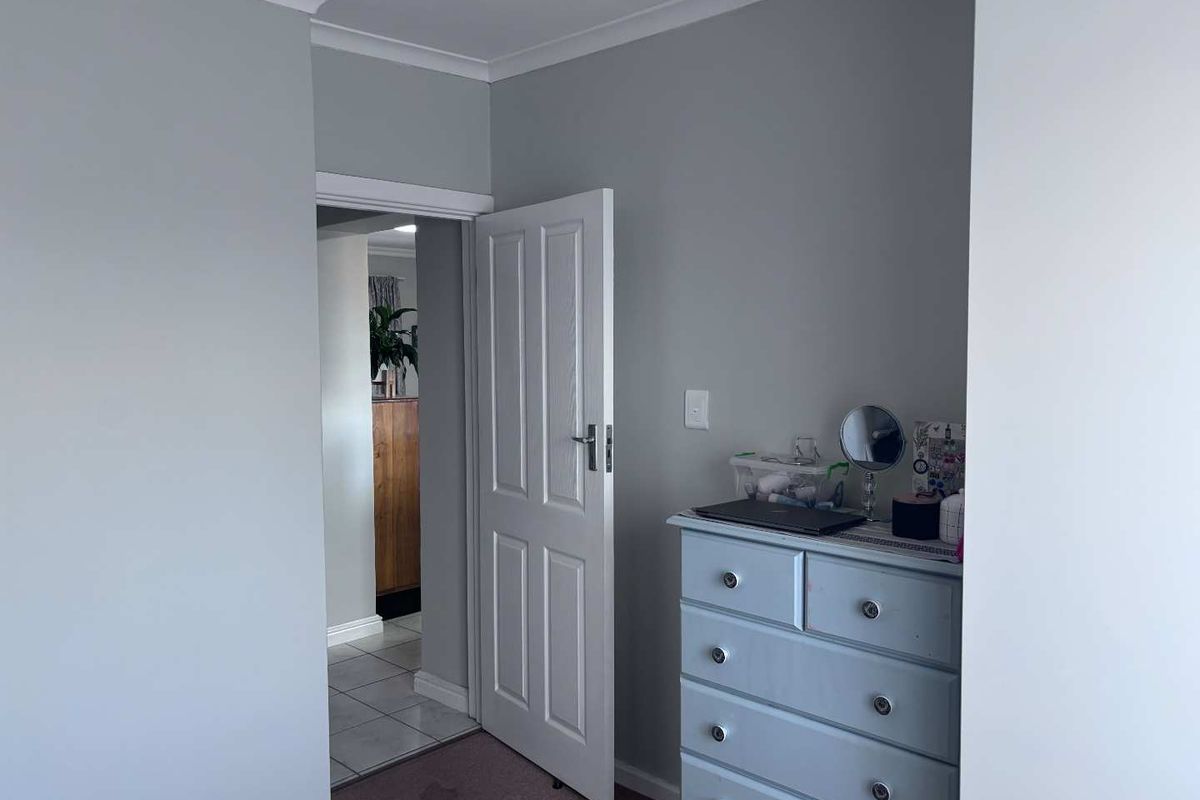 A view of a bedroom interior featuring neutral wall paint, coving, and a doorway leading to an adjacent tiled hallway.