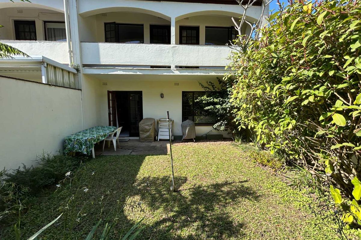 A private rear garden featuring a small lawn area and a paved patio space, accessible from the ground floor living area.
