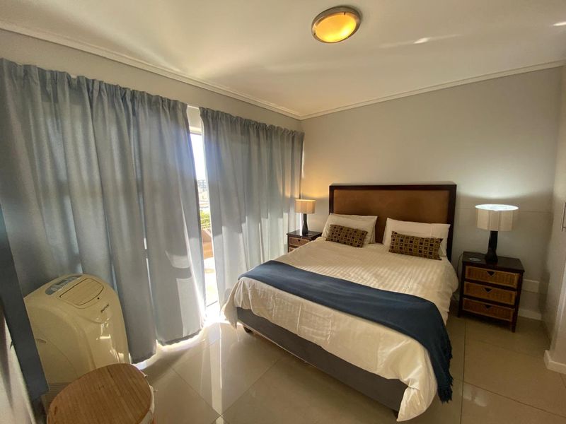A well-lit bedroom featuring tiled flooring and a sliding glass door providing access to an outdoor area.