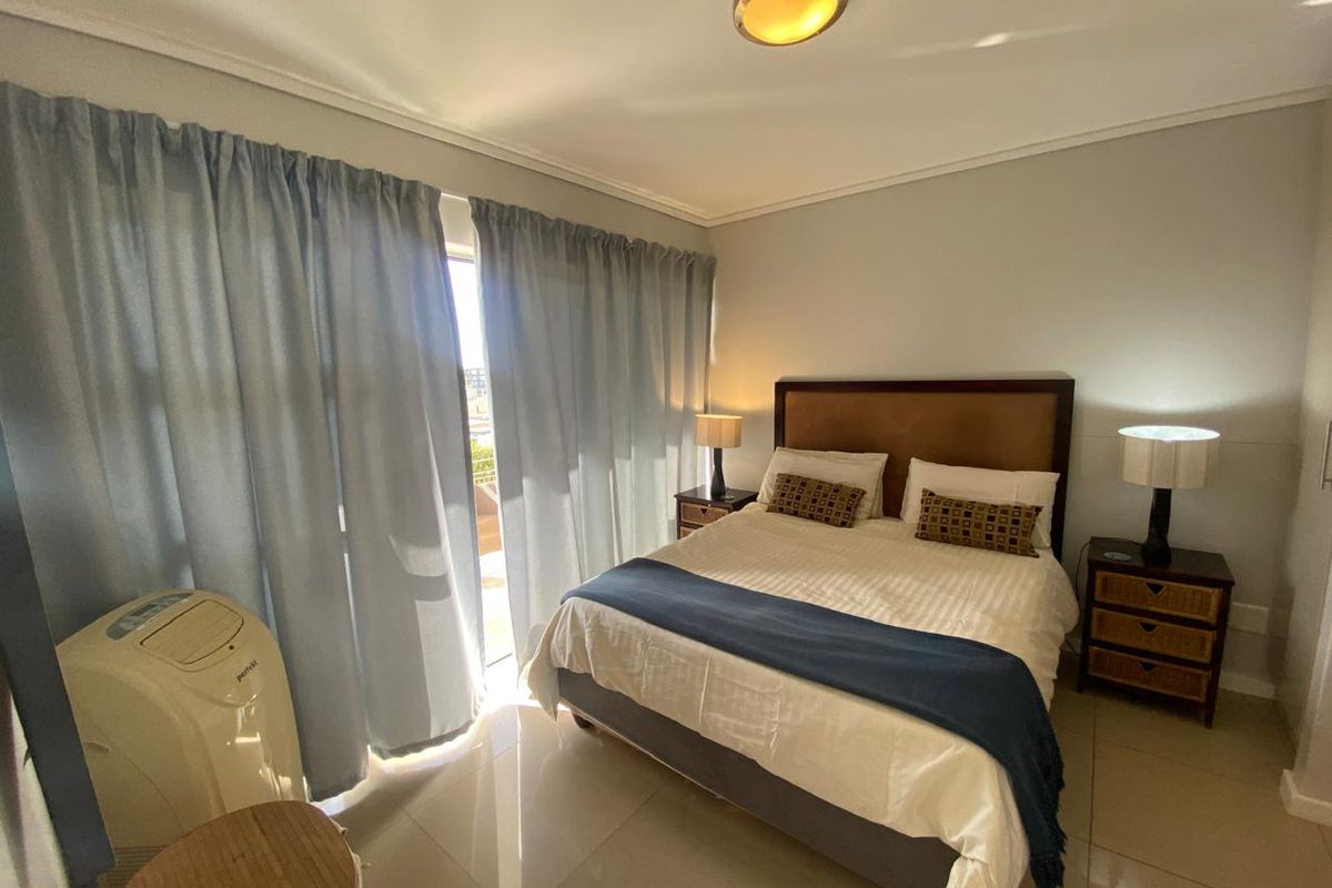 A well-lit bedroom featuring tiled flooring and a sliding glass door providing access to an outdoor area.