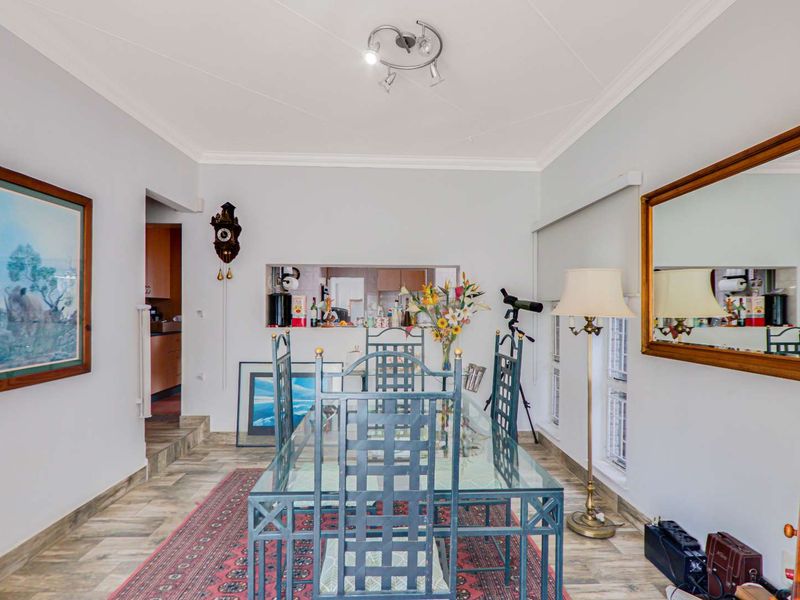 Dining room featuring wood-look tile flooring, coved ceilings, and a convenient pass-through window connecting to the kitchen area.