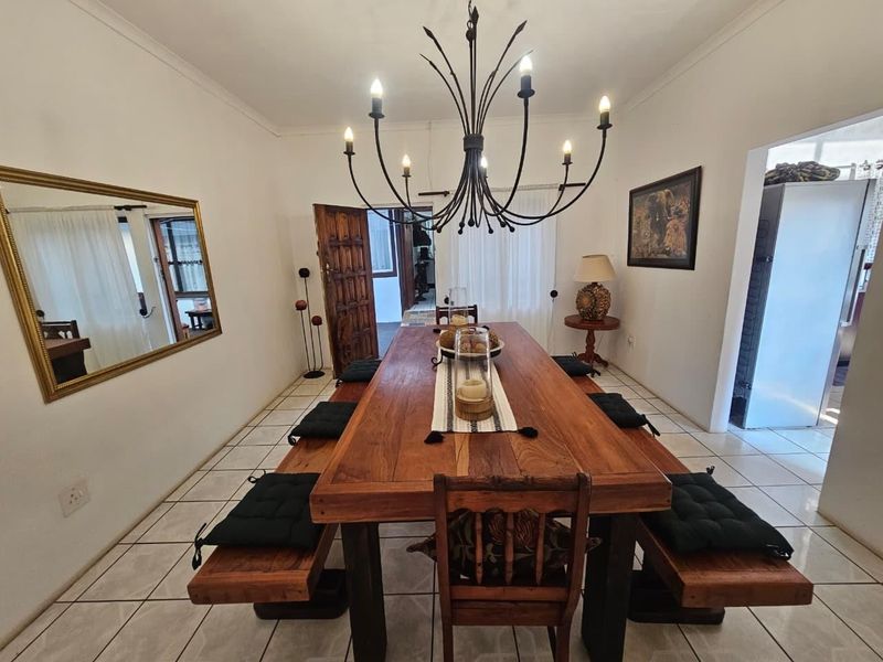 A dining room featuring ceramic floor tiles, a decorative wrought iron chandelier, and access to adjacent living spaces.