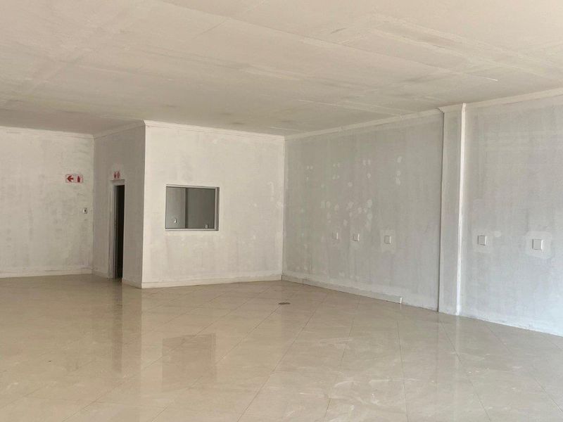 A spacious, vacant open-plan retail area featuring polished tiled flooring and neutral walls, currently awaiting final finishing touches.