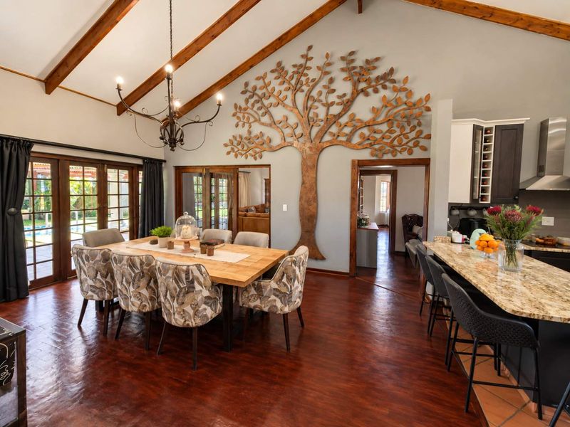 Spacious open-plan living and dining area featuring vaulted ceilings with exposed timber beams, granite kitchen countertops, and direct access to the outdoor patio.