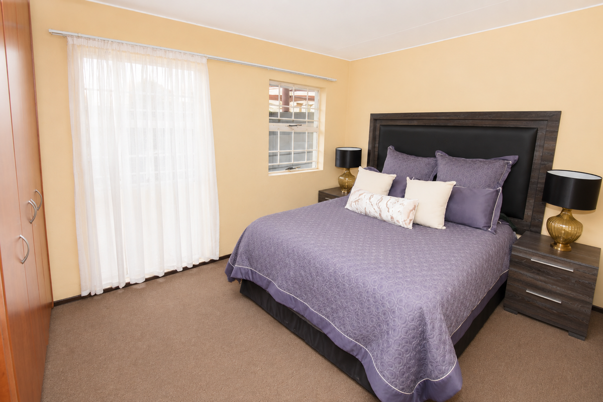 A carpeted bedroom featuring a built-in wardrobe and neutral wall finishes, providing a functional and comfortable sleeping space.