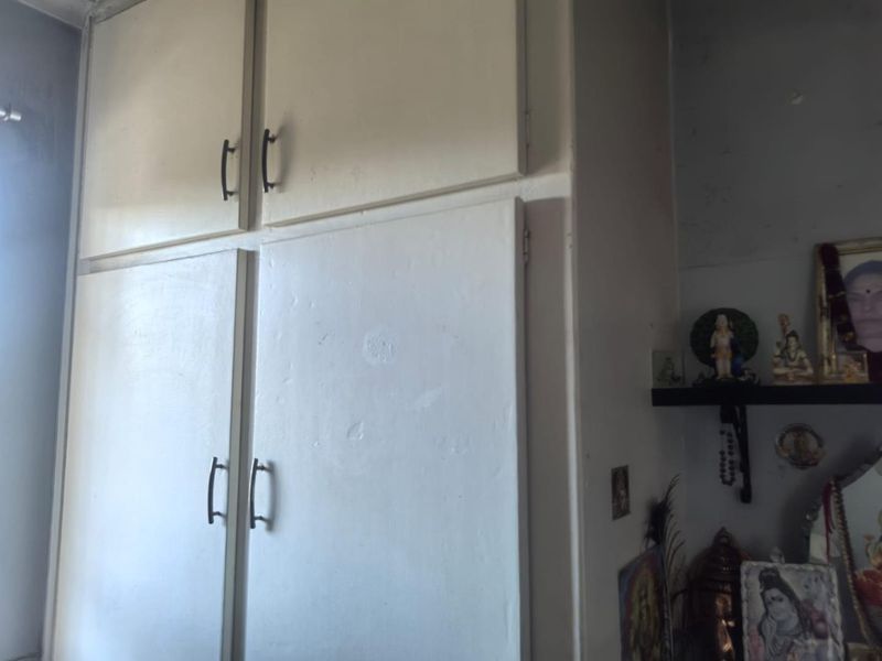 A bedroom featuring built-in storage cabinetry with visible signs of wear and paint deterioration.