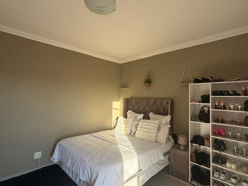 A well-maintained bedroom featuring neutral wall tones, tiled flooring, and a central ceiling light fixture.