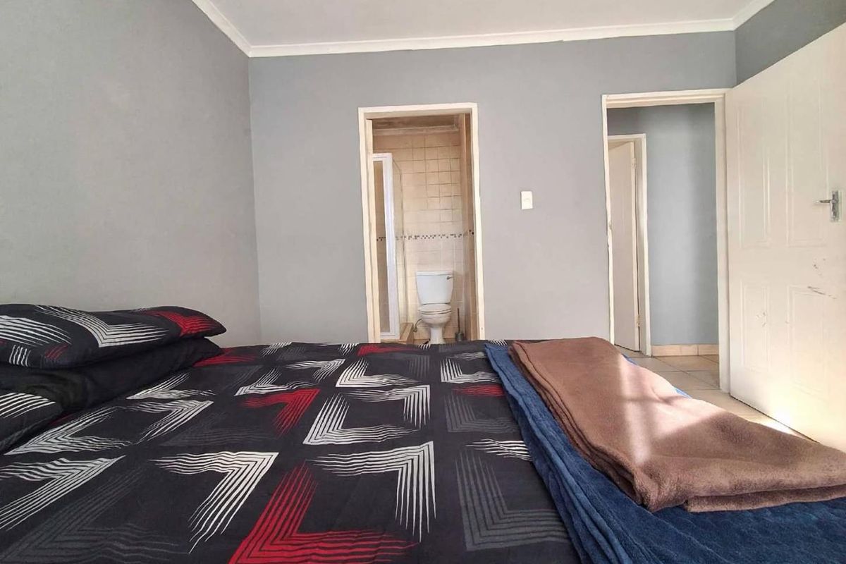 Bedroom featuring an en-suite bathroom with tiled flooring and neutral wall finishes, offering a functional layout for a townhouse residence.