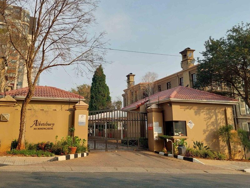 Front entrance view of Abbotsbury complex in Morningside, featuring a secure gated access point, guard house, and well-maintained perimeter wall.