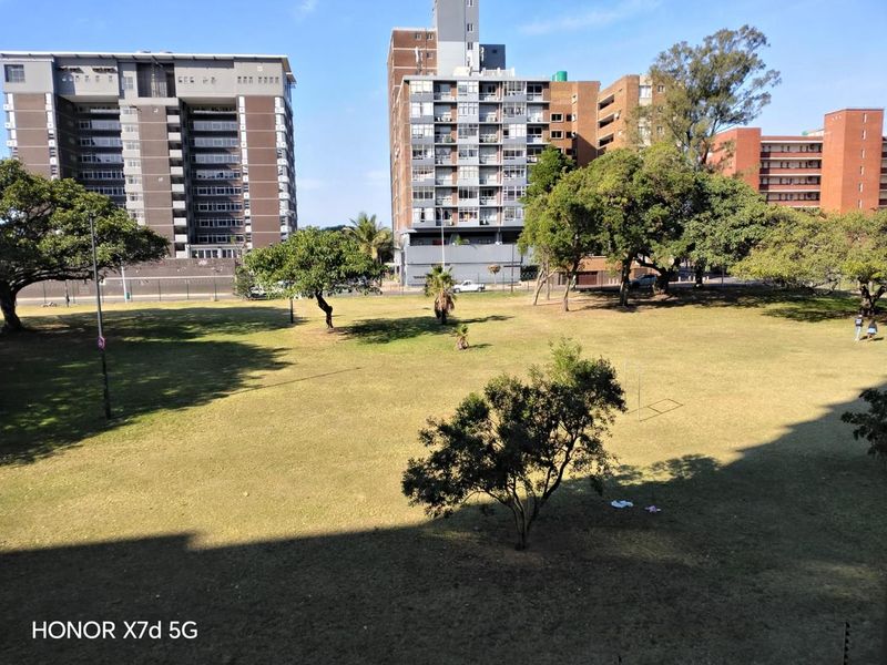 An elevated view overlooking a large communal green space and surrounding apartment buildings.