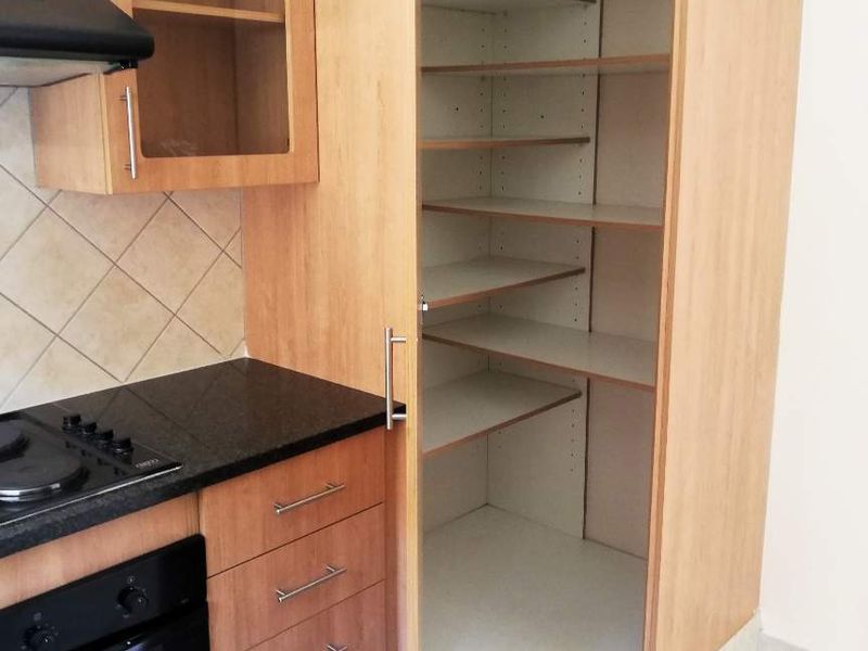 Kitchen area featuring light wood cabinetry, a built-in oven, hob, extractor fan, granite countertops, and a spacious built-in pantry cupboard.