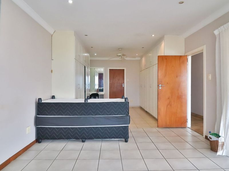 Spacious bedroom featuring extensive built-in cabinetry, tiled flooring, ceiling fan, and direct access to an outdoor area through sliding glass doors.