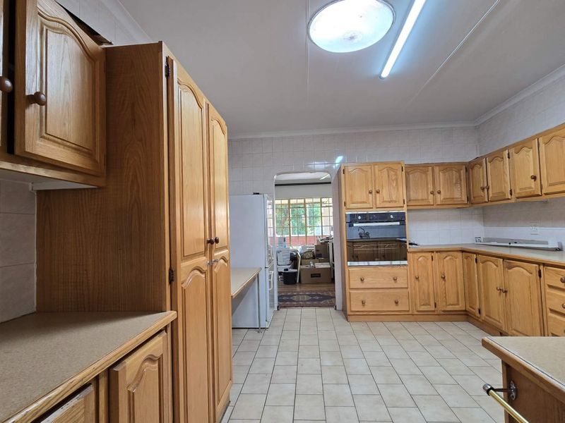 Spacious kitchen featuring extensive built-in wooden cabinetry, tiled flooring, and integrated oven, offering a functional layout with potential for modern updates.