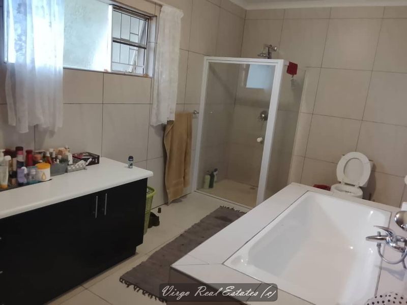 A functional bathroom featuring a built-in vanity, a separate shower enclosure, a bathtub, and neutral wall tiling.
