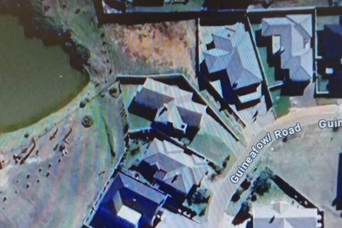 An aerial view of a residential plot located on Guineafowl Road, showing the surrounding neighborhood layout and proximity to a nearby water feature.