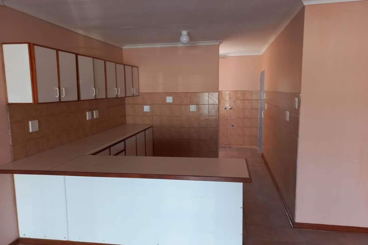 An empty, dated kitchen featuring built-in cabinetry, laminate countertops, and tiled splashbacks, offering a blank canvas for modern renovation.