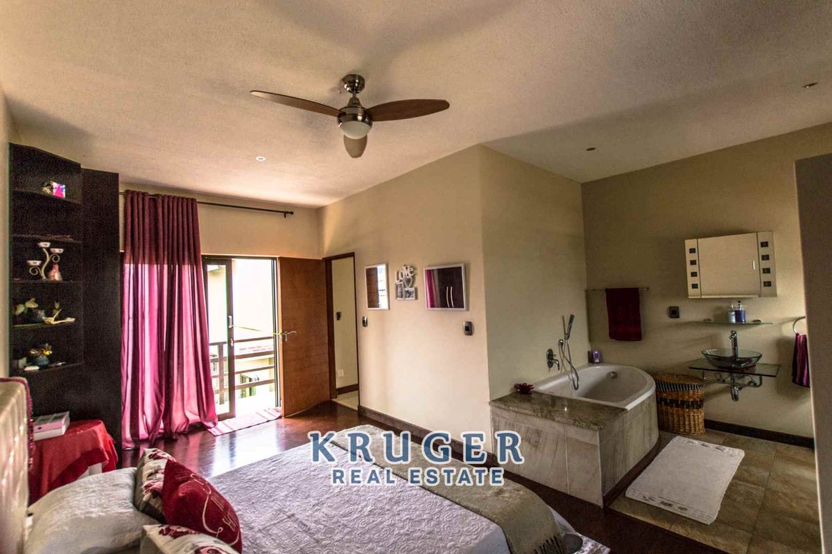 Spacious bedroom featuring an integrated en-suite bathroom with a built-in bathtub, glass vessel sink, and direct access to a private balcony.
