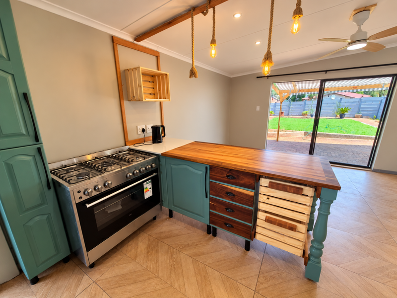 A modern kitchen featuring a gas stove, wooden countertops, custom cabinetry, and direct access to the rear patio and garden through sliding glass doors.