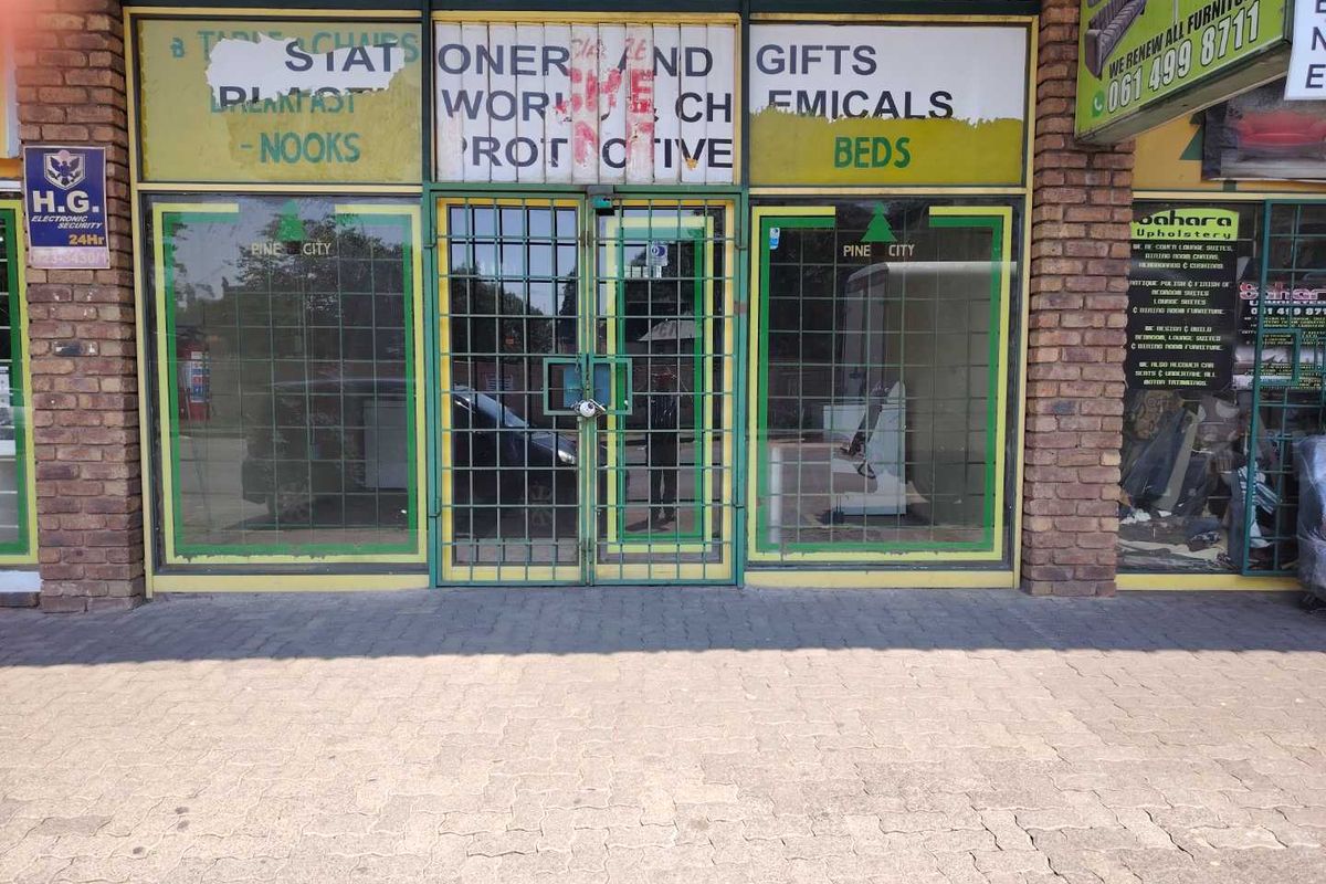 Front facade of a retail storefront featuring a brick exterior, large glass display windows, and metal security gates.