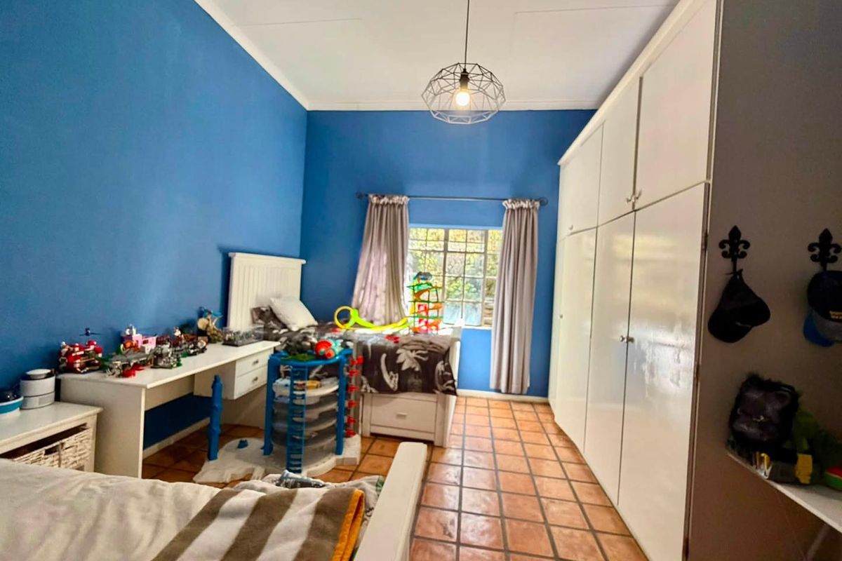 A bedroom featuring built-in cupboards, tiled flooring, and a central pendant light fixture.