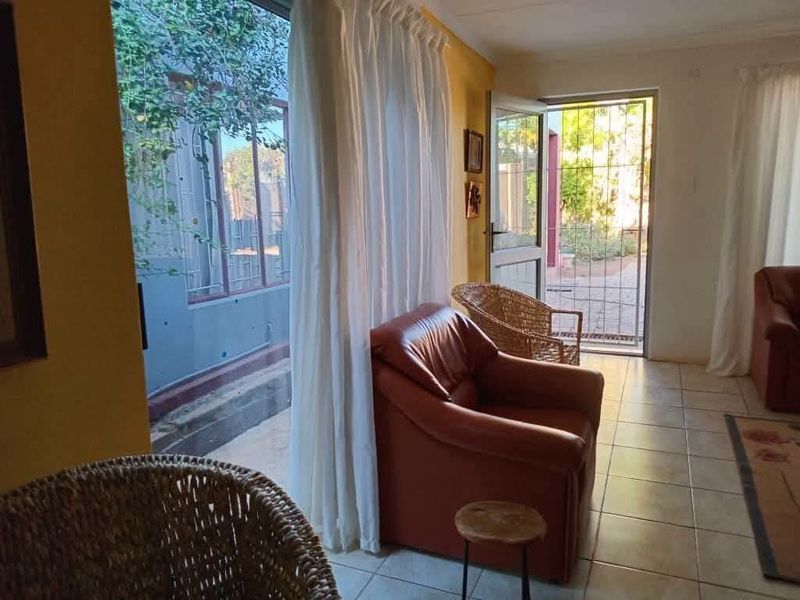 A living area featuring tiled flooring and direct access to an outdoor space through a sliding glass door and security gate.