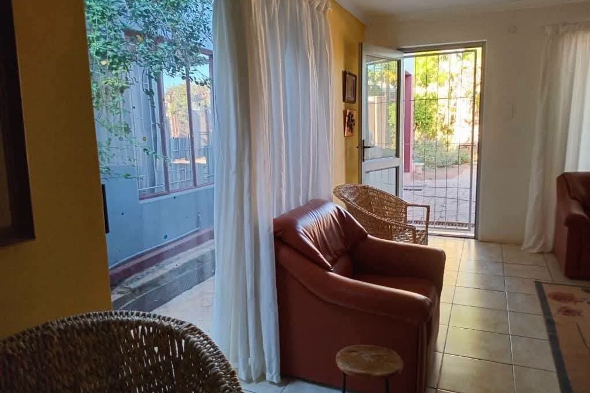 A living area featuring tiled flooring and direct access to an outdoor space through a sliding glass door and security gate.