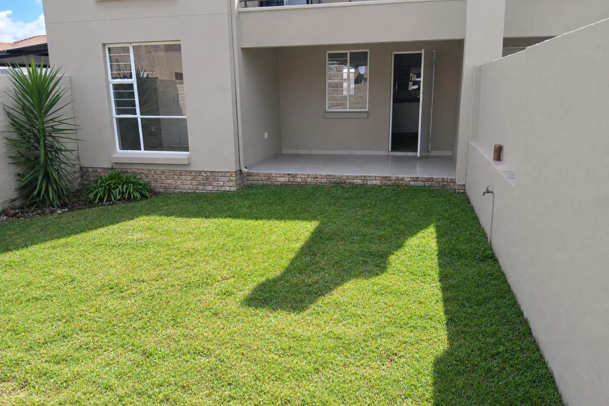 A well-maintained rear garden featuring a covered patio, a neat lawn, and a private boundary wall, providing a pleasant outdoor space.
