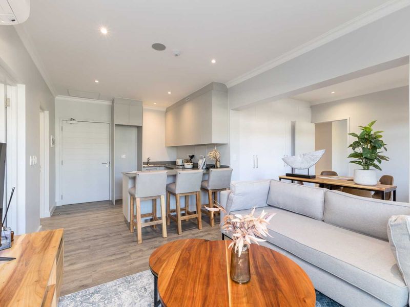 Modern open-plan living area featuring a sleek kitchen with built-in cabinetry, a breakfast island, and contemporary laminate flooring throughout.