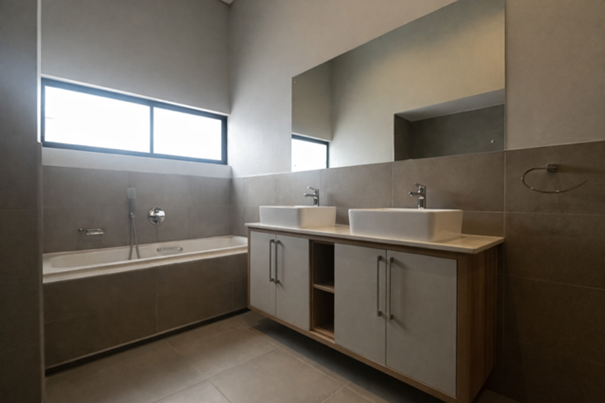 Modern bathroom featuring a double vanity with vessel sinks, a built-in bathtub, large wall-mounted mirror, and neutral floor-to-ceiling tiling.