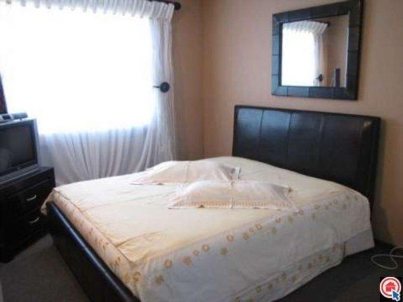 A standard bedroom featuring neutral wall tones, a window with curtains, and space for a double bed.