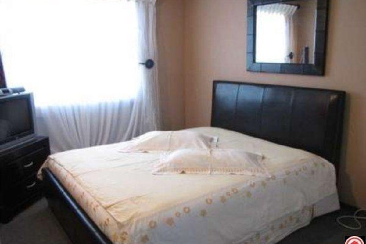 A standard bedroom featuring neutral wall tones, a window with curtains, and space for a double bed.