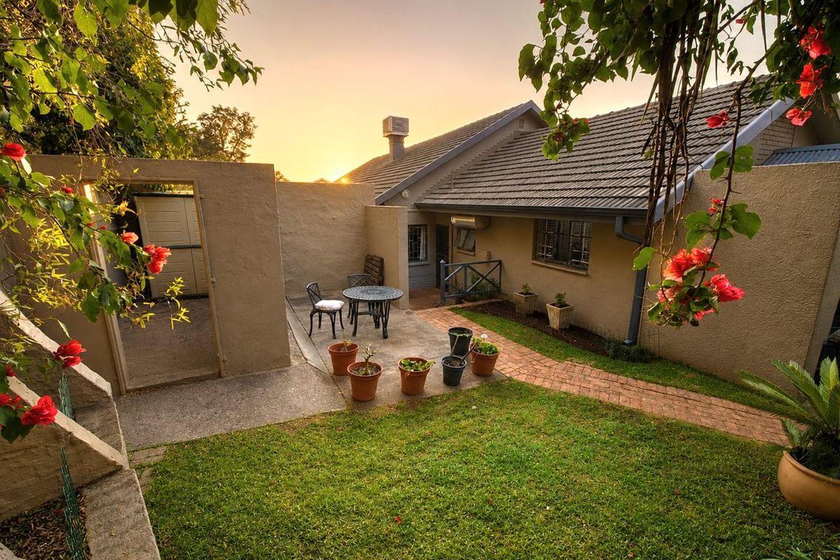 A well-maintained rear garden featuring a paved patio area, brick pathway, and established landscaping, providing a pleasant outdoor space for relaxation.