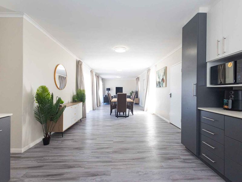 Spacious open-plan living and dining area featuring modern grey and white cabinetry, laminate flooring, and neutral finishes throughout.