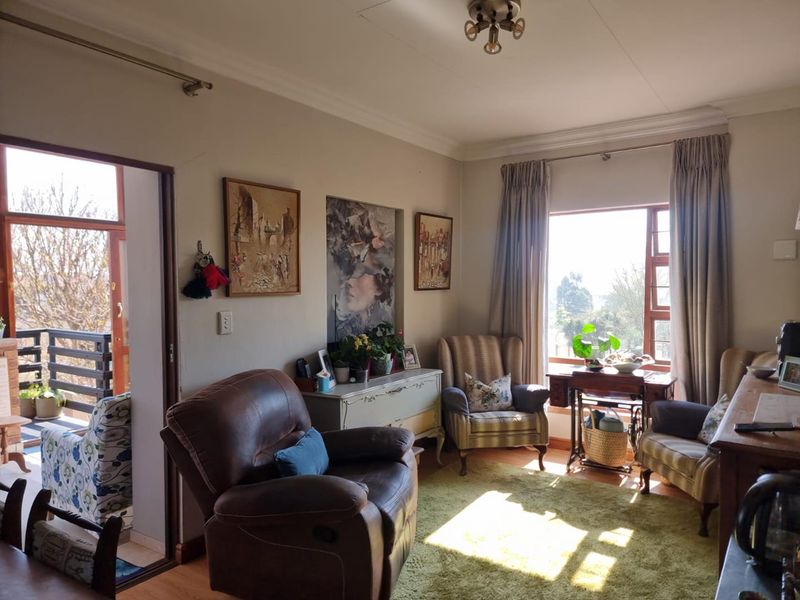A cozy living room featuring laminate flooring, natural light from a large window, and direct access to an outdoor balcony area.