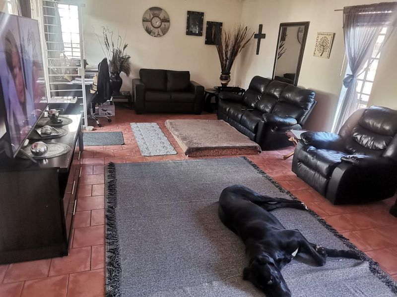 A spacious living room featuring terracotta-style tiled flooring and a security gate, providing a functional and comfortable family living area.