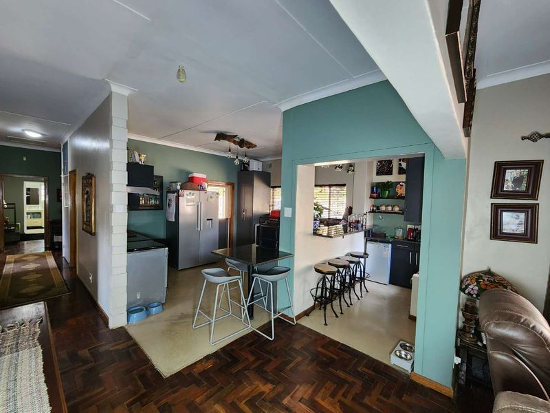 Open plan kitchen and living area featuring parquet flooring, granite countertops, and a breakfast bar, creating a functional and connected living space.