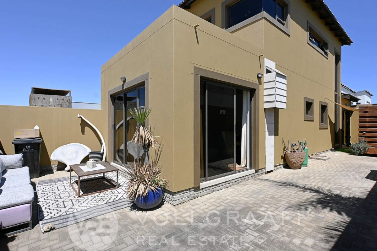 Rear exterior view of the property featuring a paved patio area and sliding glass doors providing access to the interior living space.