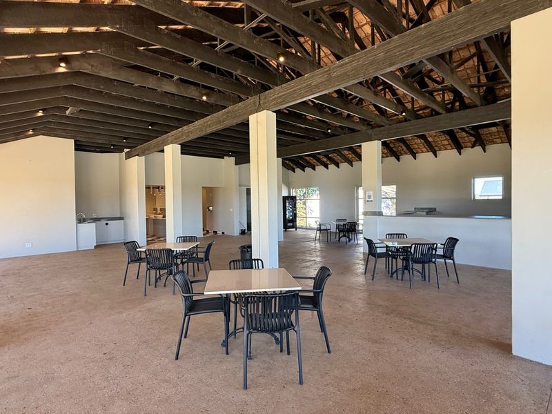 Spacious open-plan interior featuring exposed timber roof trusses, concrete flooring, and structural support columns, suitable for versatile use or event hosting.