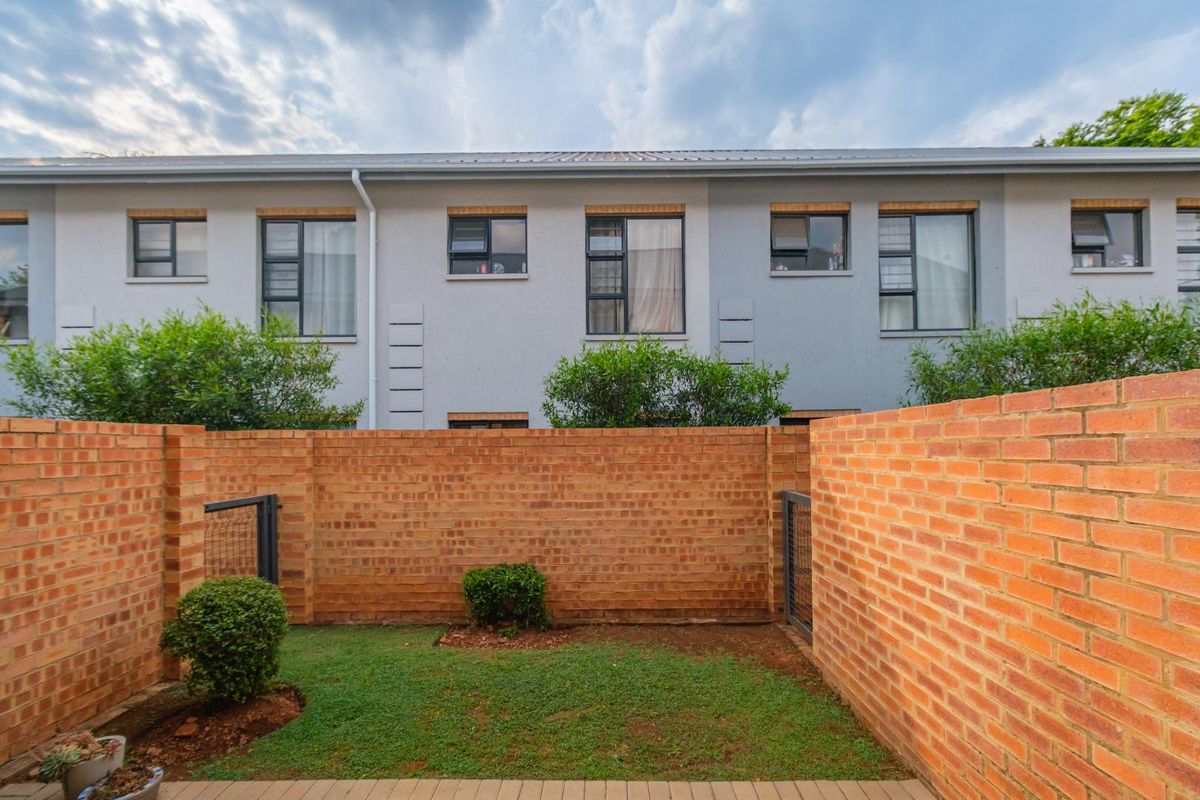 Rear view of the townhouse featuring a private enclosed garden with a brick boundary wall and aluminium window frames.